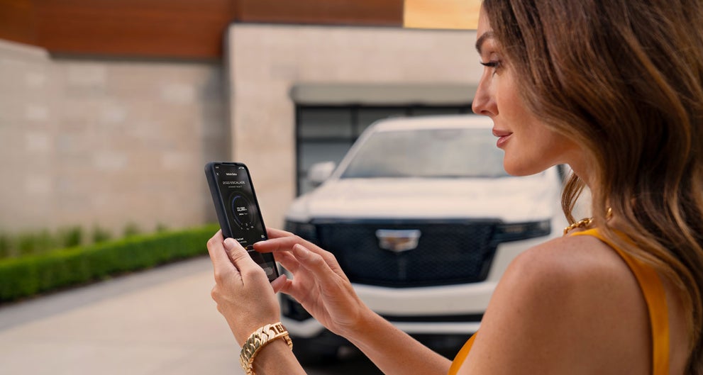 lady checking her mobile with a Cadillac vehicle background | Open Road Cadillac of Morristown in Florham Park NJ